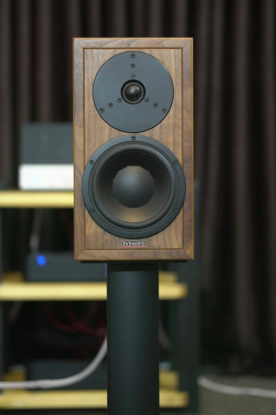 A wooden speaker sits on a stand.
