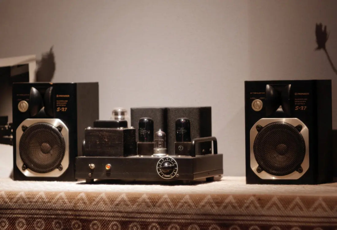 Two stereo speakers flanking a vacuum tube amplifier.