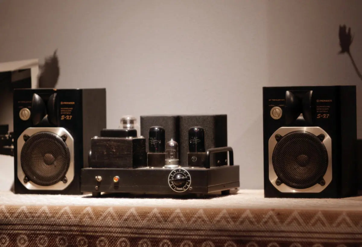 Two stereo speakers flanking a vacuum tube amplifier.